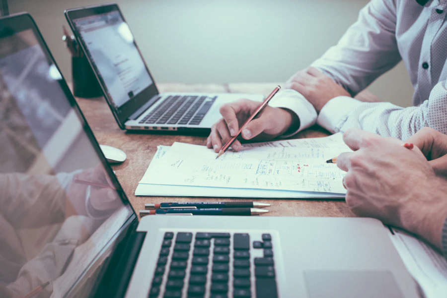 Professional reviewing documents beside a laptop